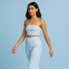 Woman wearing a light blue strapless top and high-waisted pants against a light blue background