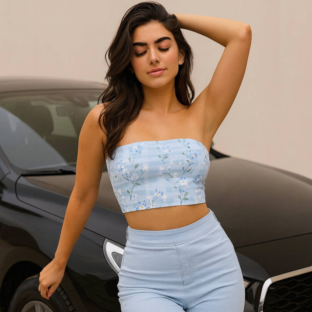 Woman in light blue strapless top and pants standing in front of a car