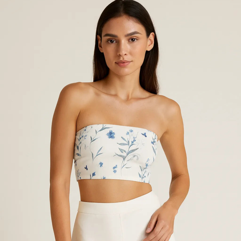 Woman wearing a floral bandeau top and white pants on a beige background