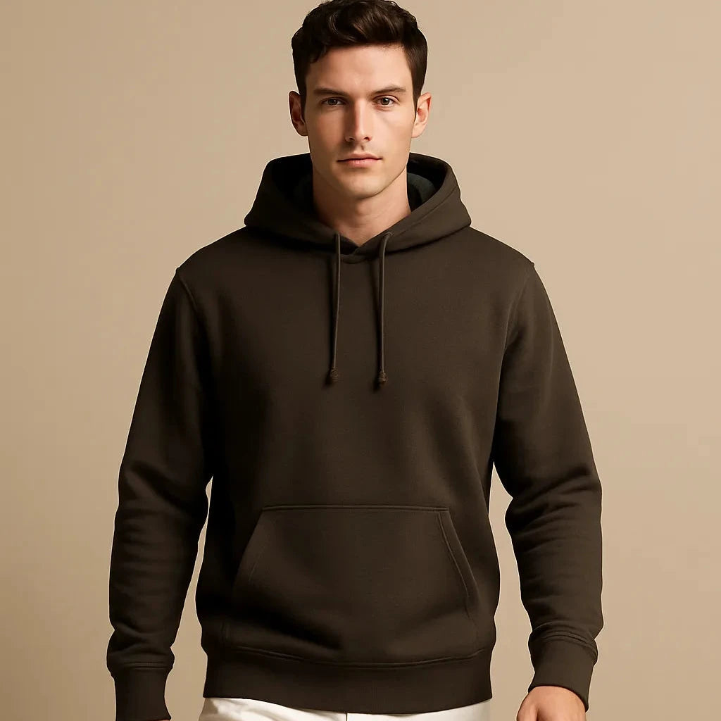 Man wearing a brown hoodie and white pants on a beige background