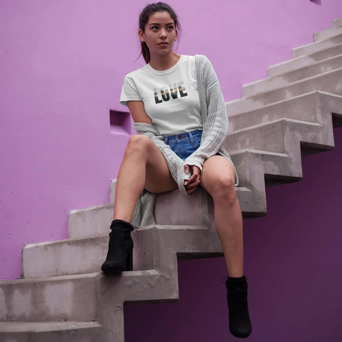 Woman sitting on a staircase against a purple wall with 'LOVE' shirt