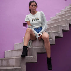 Woman sitting on a staircase against a purple wall with 'LOVE' shirt