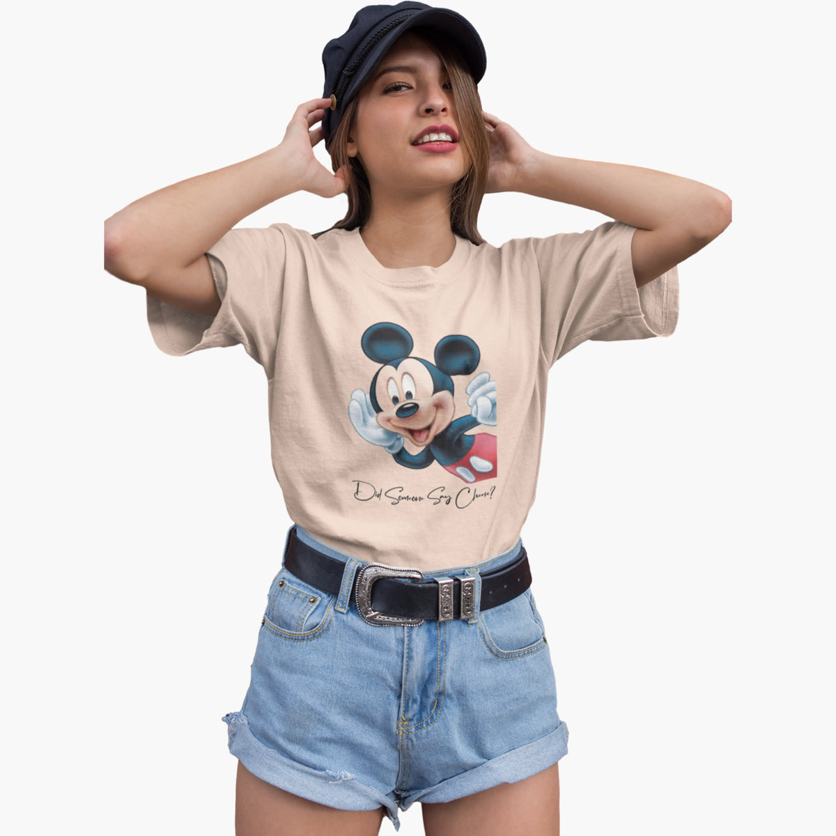 Woman wearing a beige t-shirt with a cartoon character and denim shorts on a white background