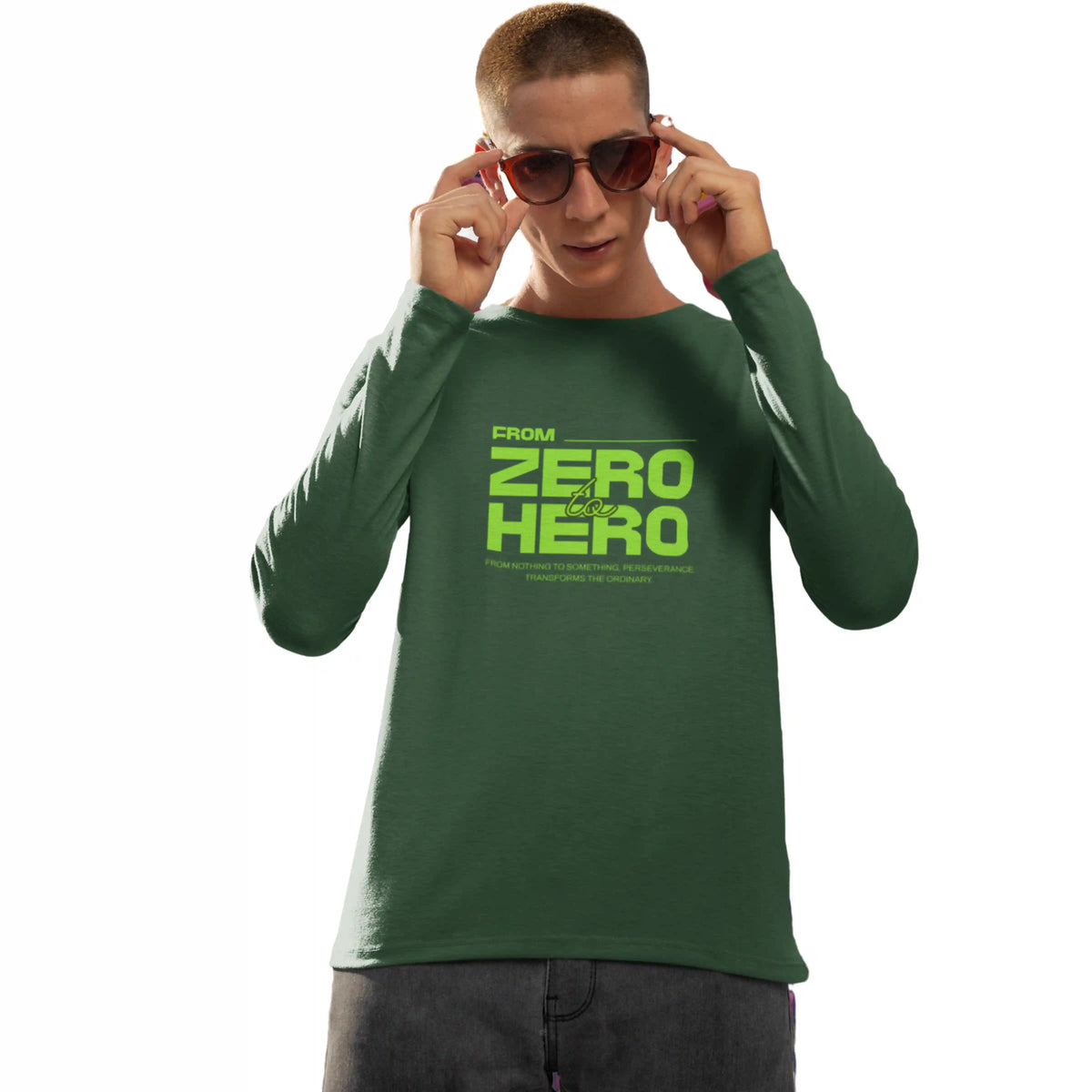Person wearing a green long-sleeve shirt with text, holding sunglasses on a white background