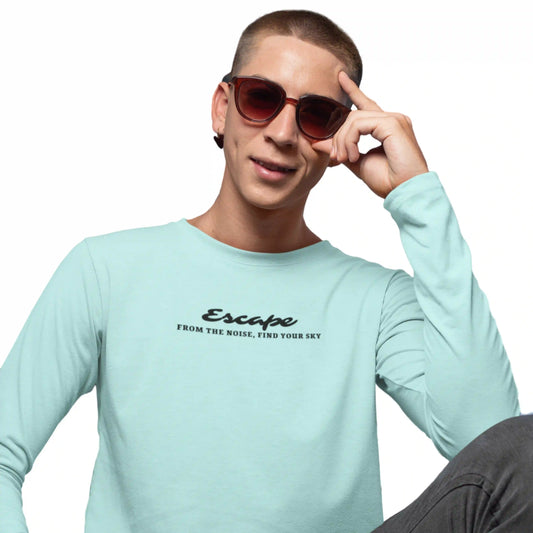 Person wearing a light blue shirt with text, posing with sunglasses on a white background