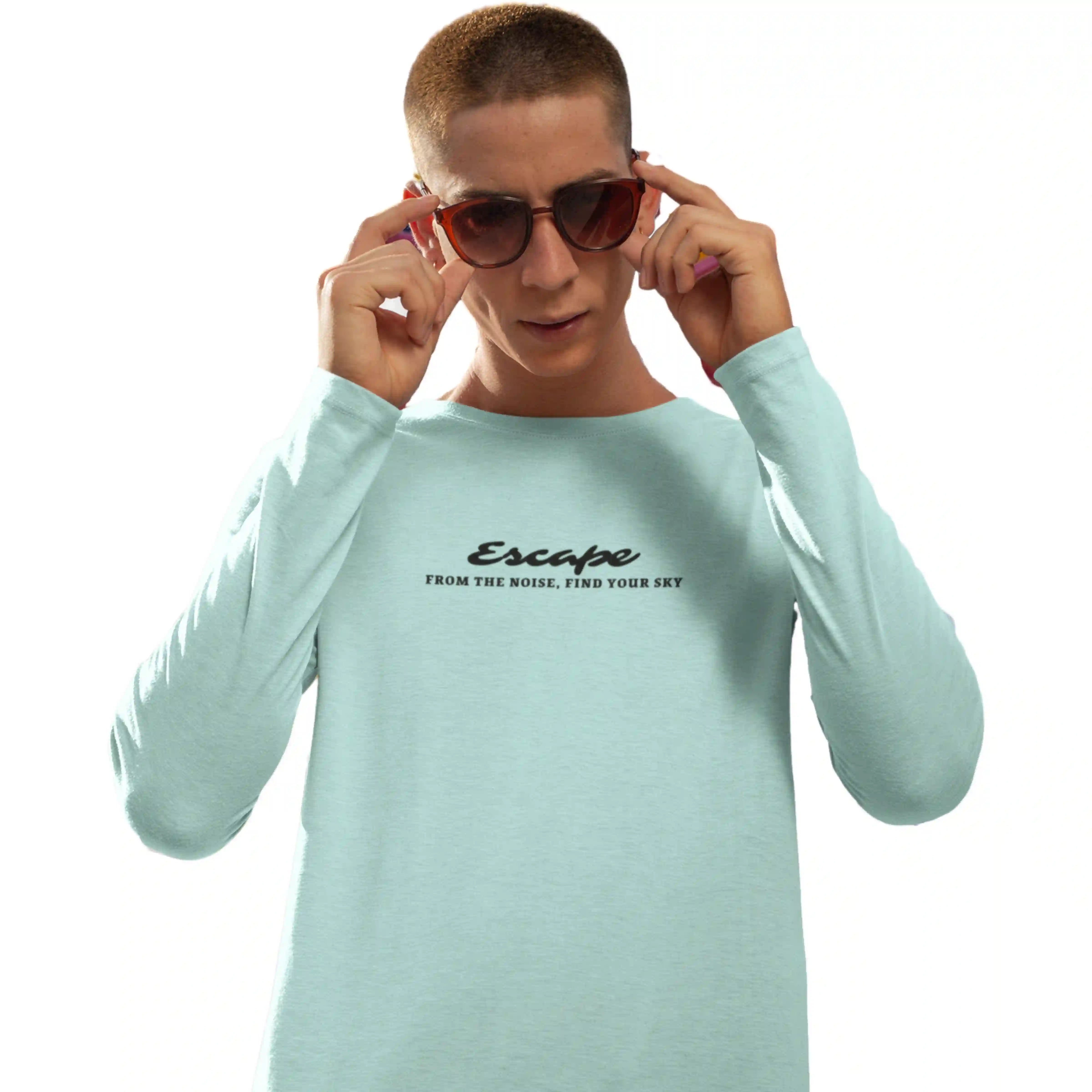 Person wearing a light blue long-sleeve shirt with text, holding sunglasses on a white background