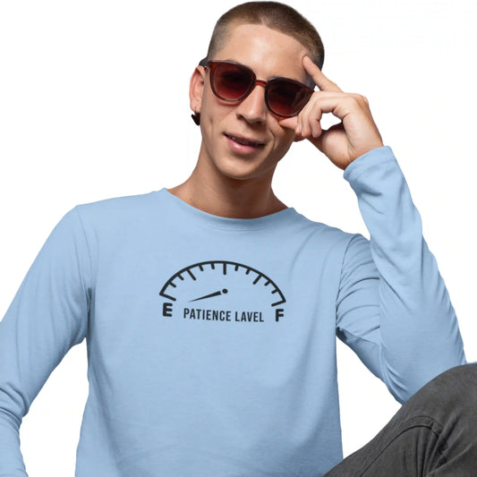 Person wearing a light blue long-sleeve shirt with a 'Patience Level' graphic, holding sunglasses.