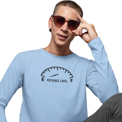 Person wearing a light blue long-sleeve shirt with a 'Patience Level' graphic, holding sunglasses.