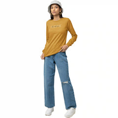 Person wearing a mustard yellow long-sleeve shirt and blue jeans on a white background