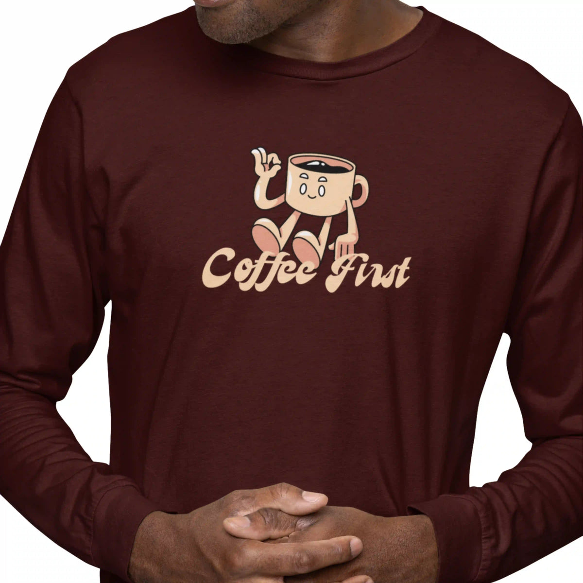 Person wearing a maroon long-sleeve shirt with a cartoon coffee cup design and 'Coffee First' text.