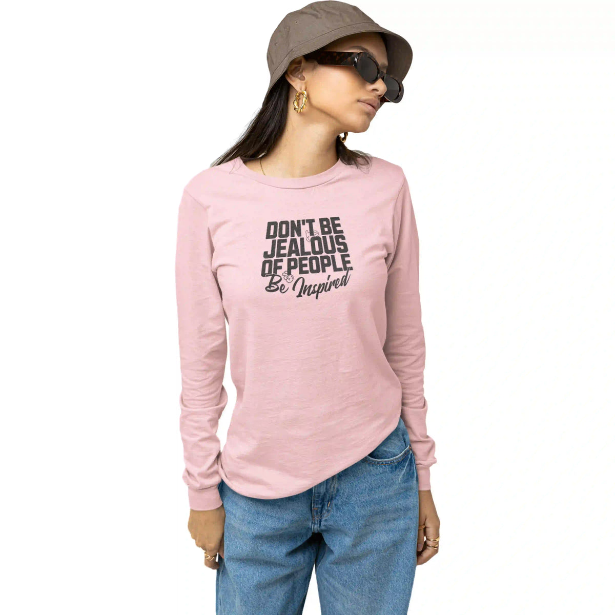 Person wearing a pink long-sleeve shirt with text, blue jeans, and a hat on a white background