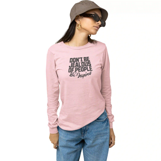 Person wearing a pink long-sleeve shirt with text, blue jeans, and a hat on a white background