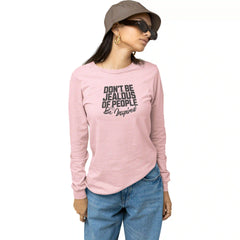 Person wearing a pink long-sleeve shirt with text, blue jeans, and a hat on a white background