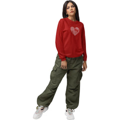 Person wearing a red sweatshirt with a heart design and green pants on a white background