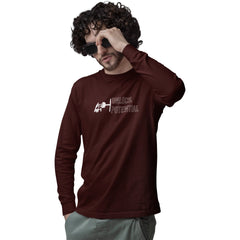 Man wearing a brown long-sleeve shirt with a logo and text, holding sunglasses to his face on a white background.