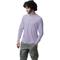 Man wearing a light purple long-sleeve shirt and green cargo pants on a white background
